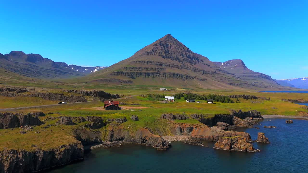 The drone’s eye unveils the majestic mountains of Djúpivogur, showcasing dramatic cliffs and vibrant greenery that define Iceland’s rugged charm.
