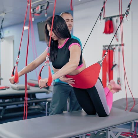 young woman is doing working out with personal trainer at fitness center. modern rehabilitation physiotherapy male worker with client. woman is training after hard disease.