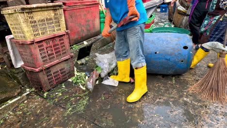 person cleaning up trash in a busy market