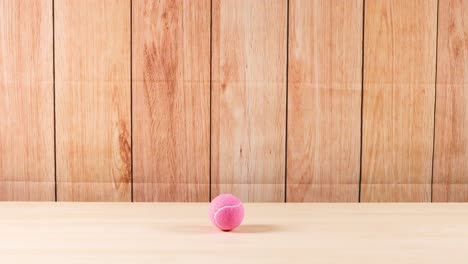 la pelota rosa rebota contra el fondo de madera repetidamente