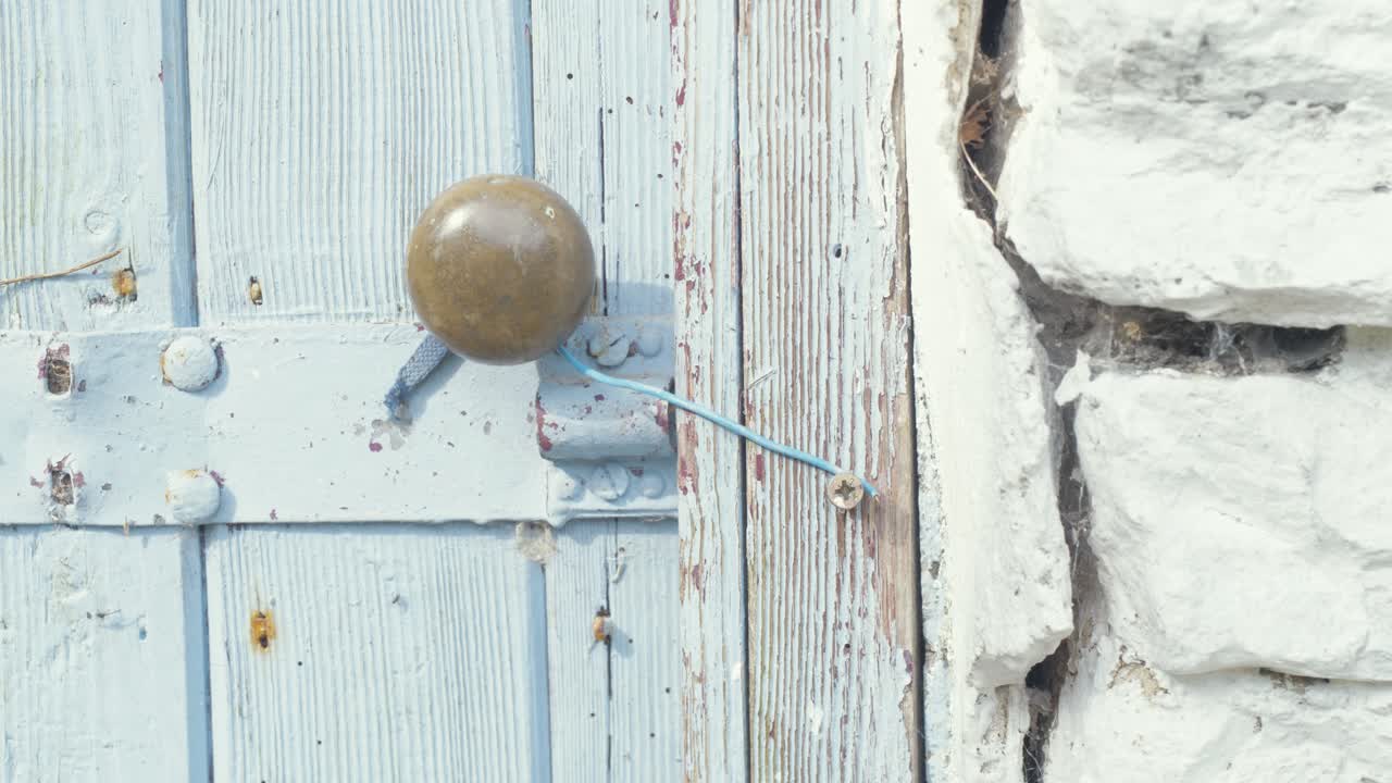 Closing door on old stone cottage with twine latch
