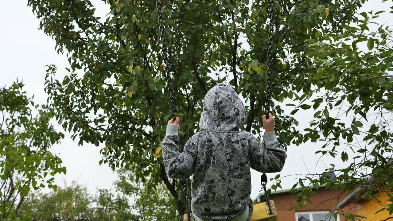 el columpio se mueve con un niño, un niño borroso y un fondo