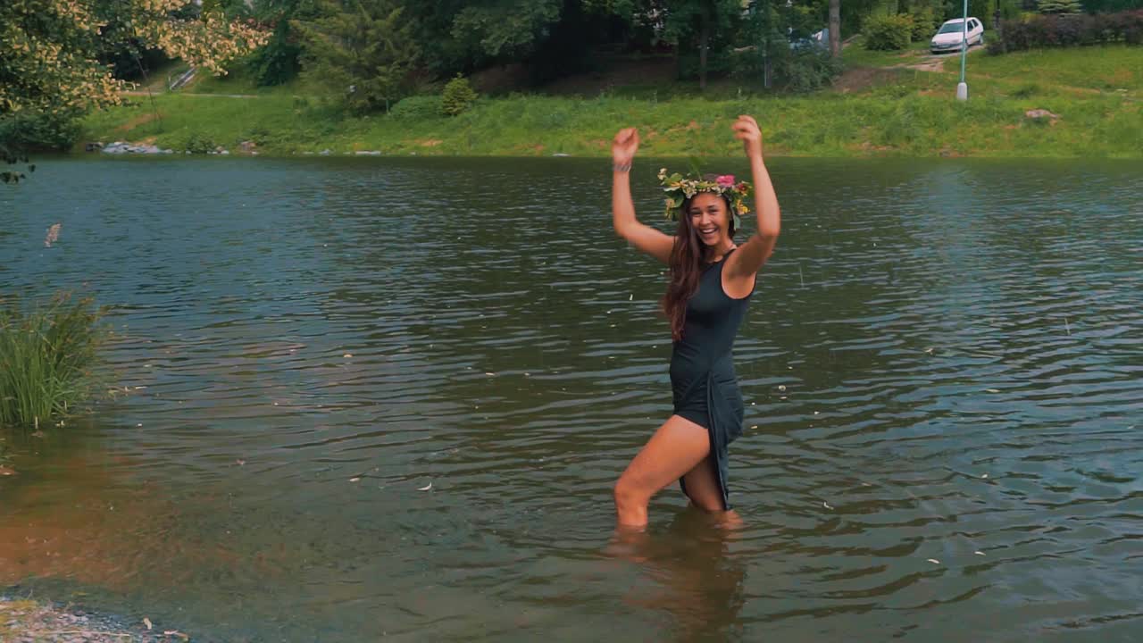 Hipster woman frolicking in lake water wearing colorful circular bouquet on head