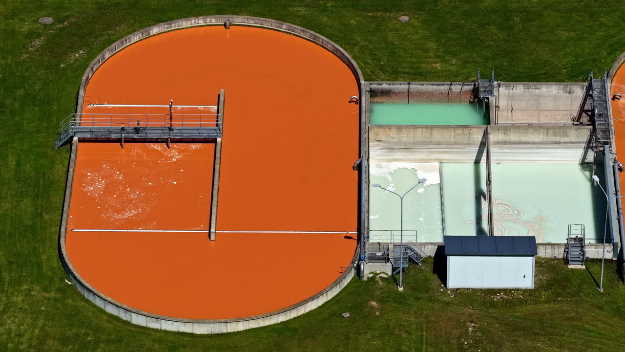 A wastewater treatment plant with large circular tanks and pools, aerial view