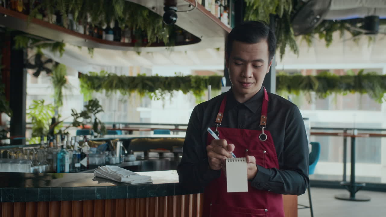 Asian Waiter Taking Clients Order in Restaurant