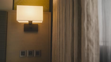 shot of white and beige curtains catching a breeze in bedroom hotel interior