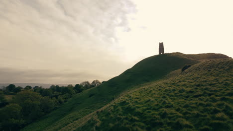 a drone shot of a hill in somerset uk called glastonbury tor