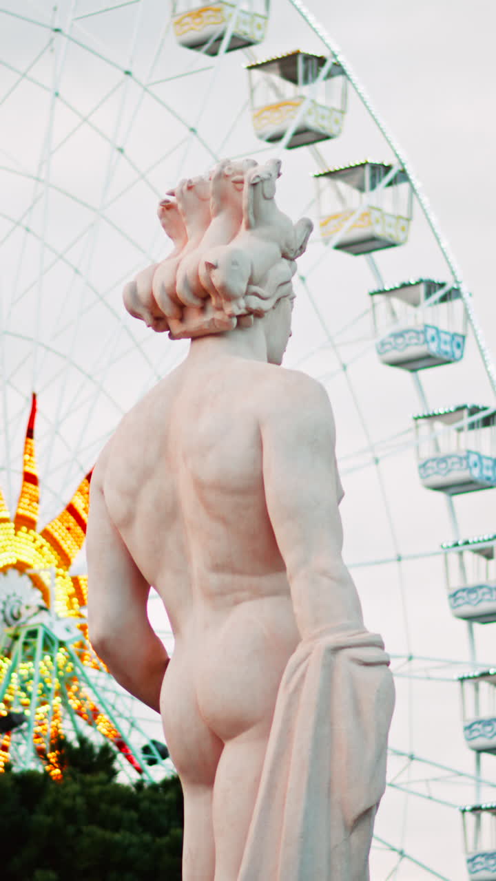 Nice, France - December 8, 2024: Apollo statue in the Fontaine du Soleil at Place Massena with a ferris wheel on the background. Vertical