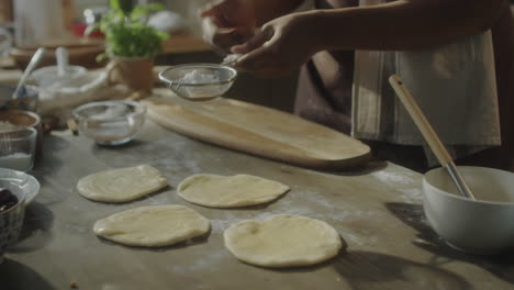 a person sifting powder over dough while baking