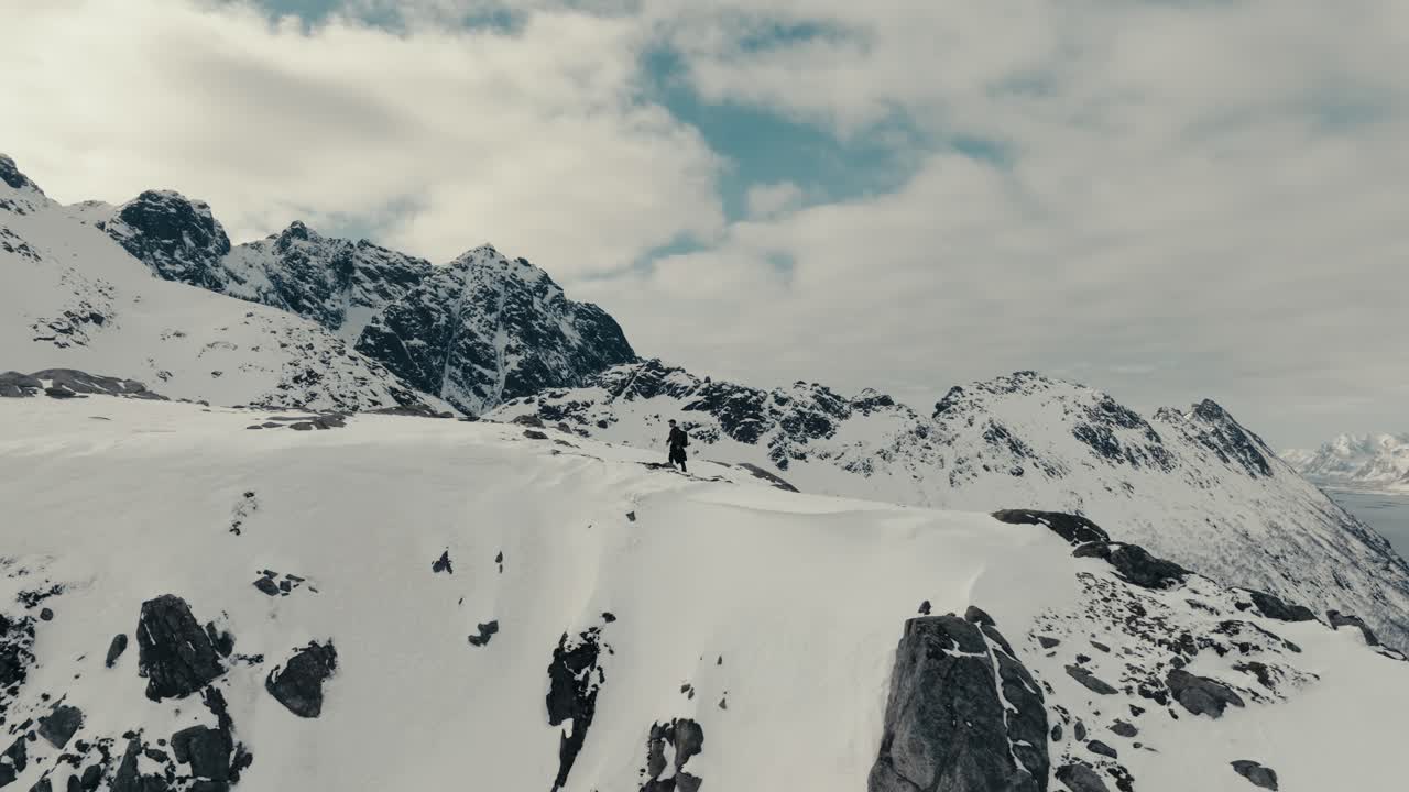 Hiker Climbs On Top Of The Snowy Mountain In Norway. - aerial shot
