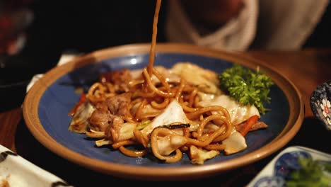 chopsticks lifting yakisoba noodles from plate