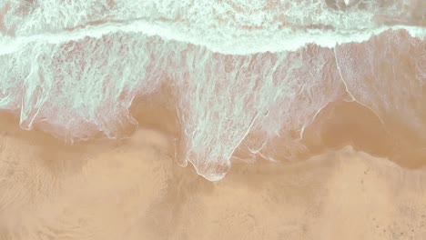 Static-top-shot-aerial-drone-showing-endless-wild-sea-waves-breaking-on-the-sandy-coast-in-slow-motion