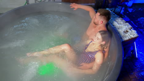 man and woman in love sit hugging in hot tub. happy relaxed people in spa top view.