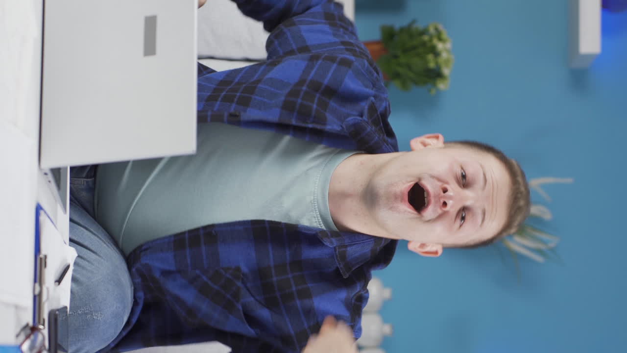 Vertical video of Home office worker man experiencing joy looking at camera.