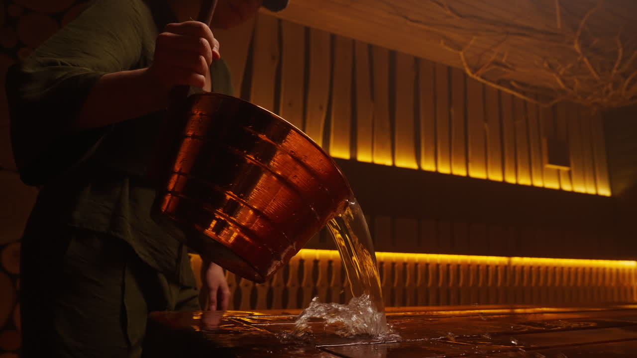 Woman pouring water into a sauna