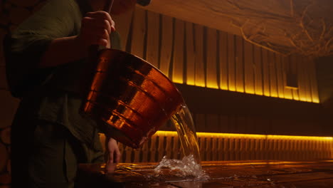 woman pouring water into a sauna