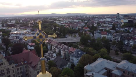 church cross on top of the cathedral in freiburg im breisgau during sunset with town view in background, germany