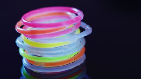 Animation-of-multiple-colorful-neon-glow-sticks-over-black-background