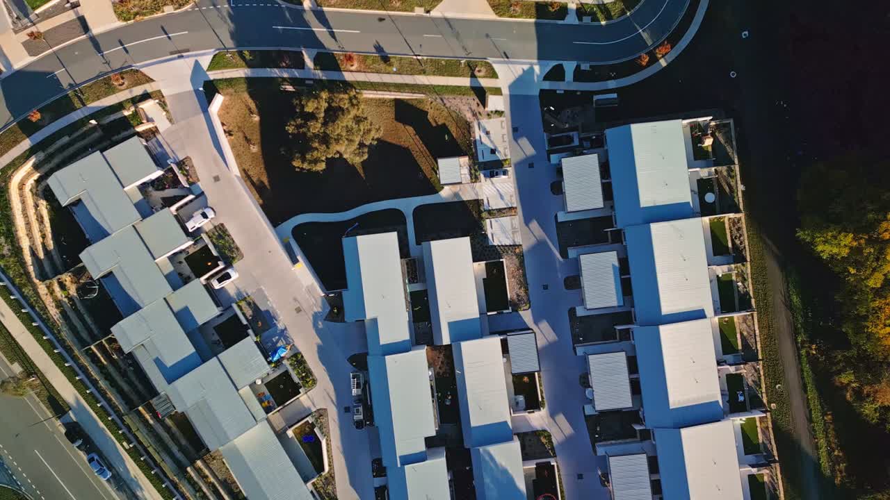 Drone footage of a newly built Canberra estate featuring bright white-roofed townhouses in neat rows.