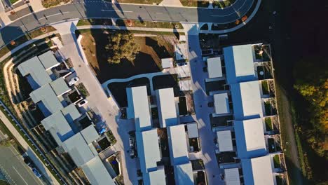 drone footage of a newly built canberra estate featuring bright white-roofed townhouses in neat rows.