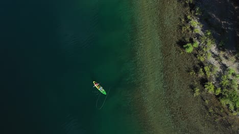 Aerial-top-down-of-two-trained-fishers-catching-trouts-with-dry-fly-technique-near-the-shore-in-Lake-Steffen,-Patagonia-Argentina