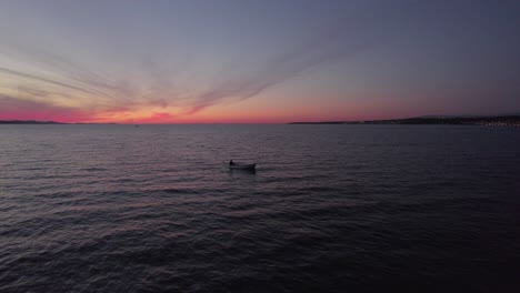 Pequeño-Barco-De-Pesca-Recreativa-Navegando-En-Un-Mar-Oscuro-Y-Tranquilo-Durante-El-Crepúsculo,-Aéreo