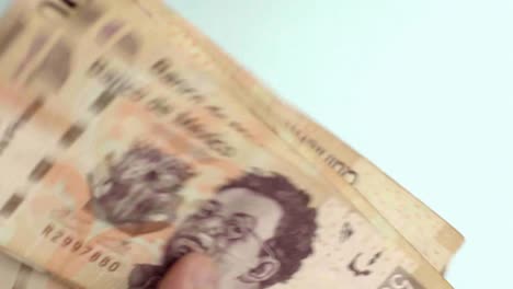 close-up of fingers counting mexican 500 peso bills, blue background