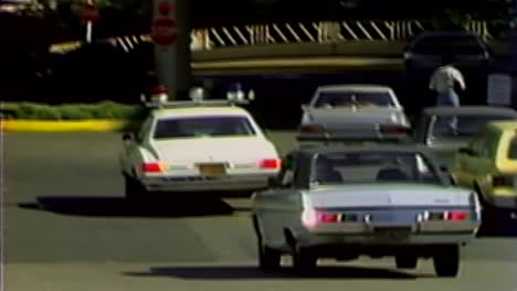 coche de policía de 1978 conduciendo en un estacionamiento