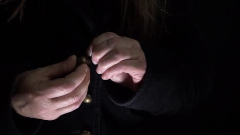 woman buttoning up a black velvet coat medium shot