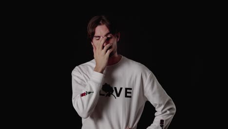 trendy young man shaking head, giving facepalm gesture, wide, black background