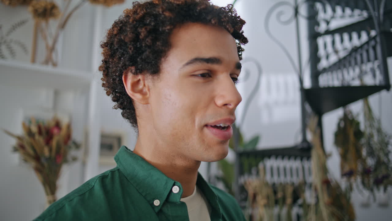 Smiling african man speak in flower store. Closeup cheerful curly guy in shop.