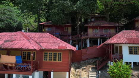 Island-Hill-Huts-in-lush-Jungle-fores,-emerald-waters-lagoon