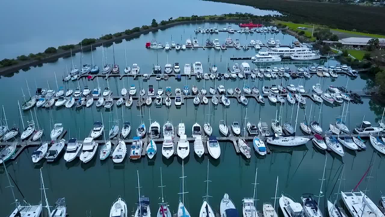Flygfoto över lyxbåtar förtöjda i en lugn marina en lugn dag.