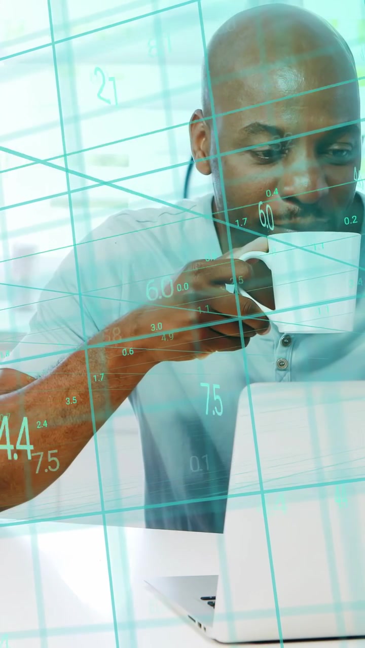 Man working, leaning to laptop, showing teal grid, typing, sipping from mug, analyzing tech data