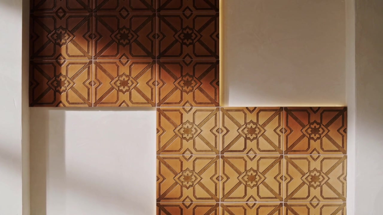 Luce solare che scivola dalla finestra attraverso piastrelle marroni a fantasia e pannelli bianchi, proiettando un'ombra.