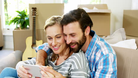 Cute-couple-sitting-against-a-cardboard-taking-a-selfie