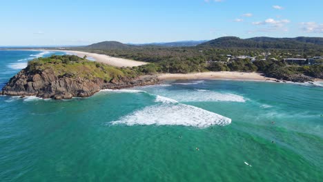 norries headland with surfers surfing at cabarita beach in summer - unspoiled beach in nsw, australia