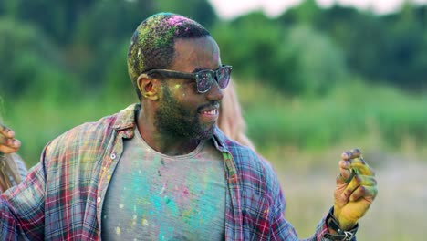 joven guapo con gafas oscuras y atractiva chica rubia divirtiéndose, riendo y bailando en las vacaciones de holi