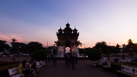 Monumento-Patuxai-Iluminado-Al-Atardecer,-Vientiane-Con-Gente-En-Primer-Plano