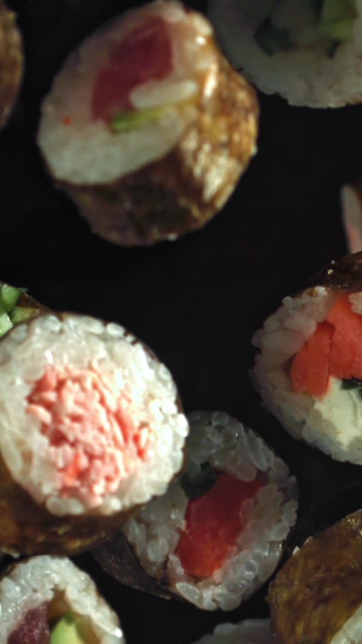 Nahaufnahme von verschiedenen frischen Sushi-Rollen auf dunklem Hintergrund