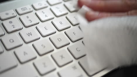 una mano que limpia el polvo y los gérmenes del teclado sucio de la computadora con una toallita desinfectante antibacteriana para mantener el hogar familiar saludable y a salvo de virus o bacterias contagiosas