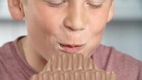 close up of boy eating bar of chocolate