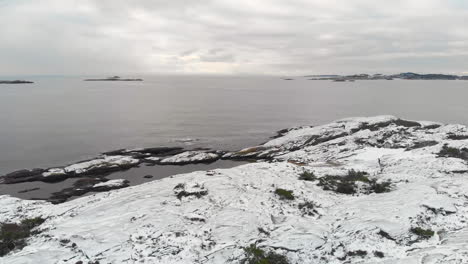 aerial of coastline with snow on rocks and waves. in norway 4k