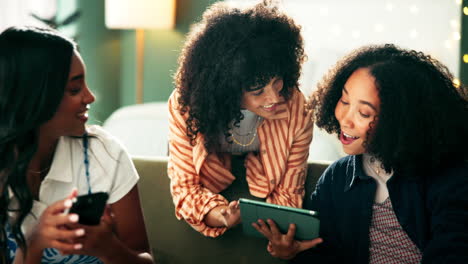 three friends laughing together using a tablet