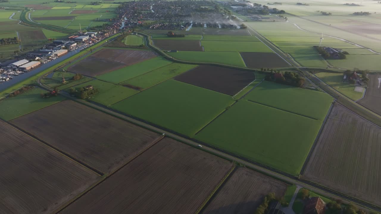 Aerial view of rural landscape near Workum at sunrise with a traditional farm and modern wind turbine in Friesland