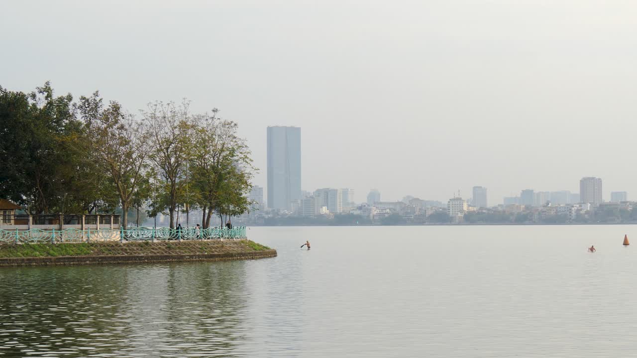 edificios de la ciudad en la costa distante, tráfico que viaja cerca de la orilla del agua