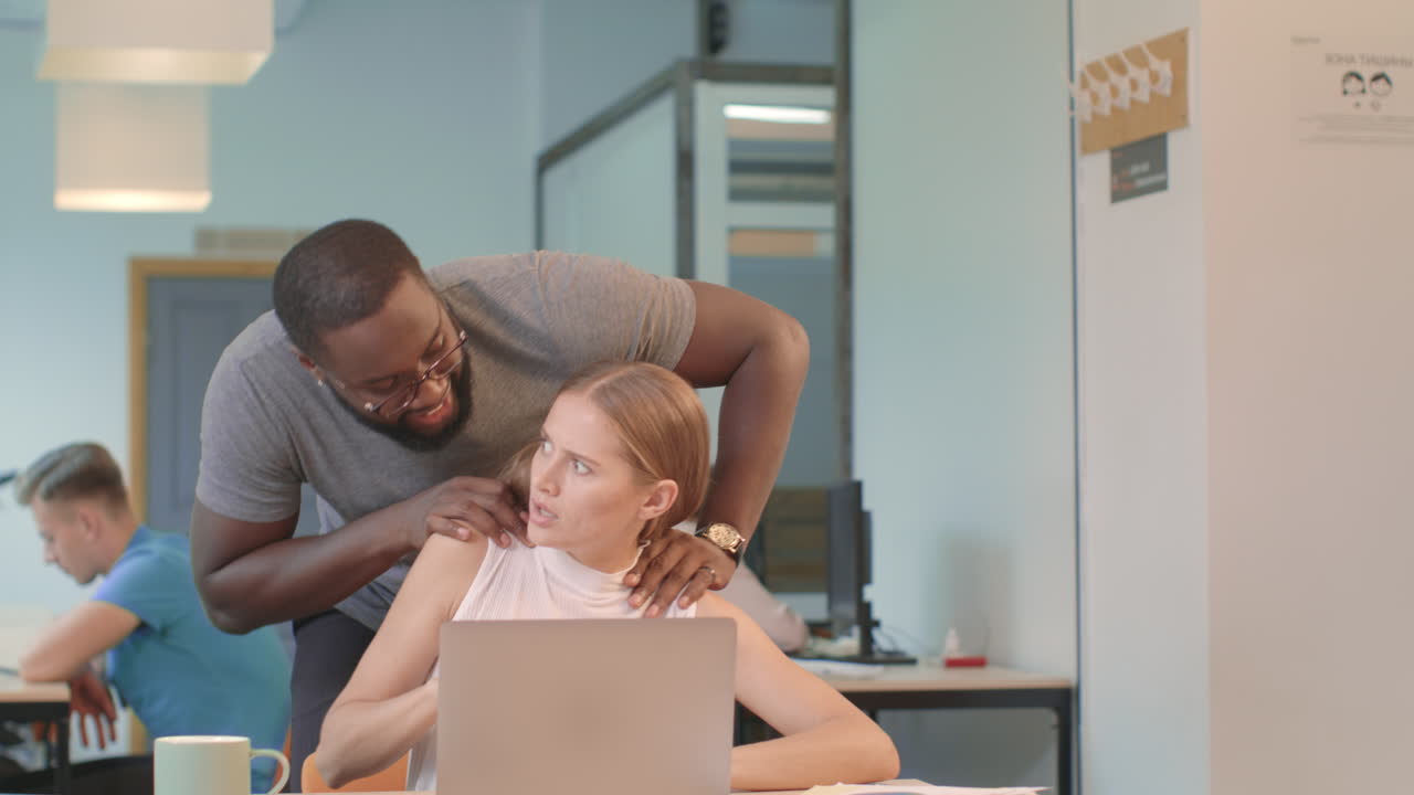 Business woman working on notebook at coworking. Black man trying make massage.