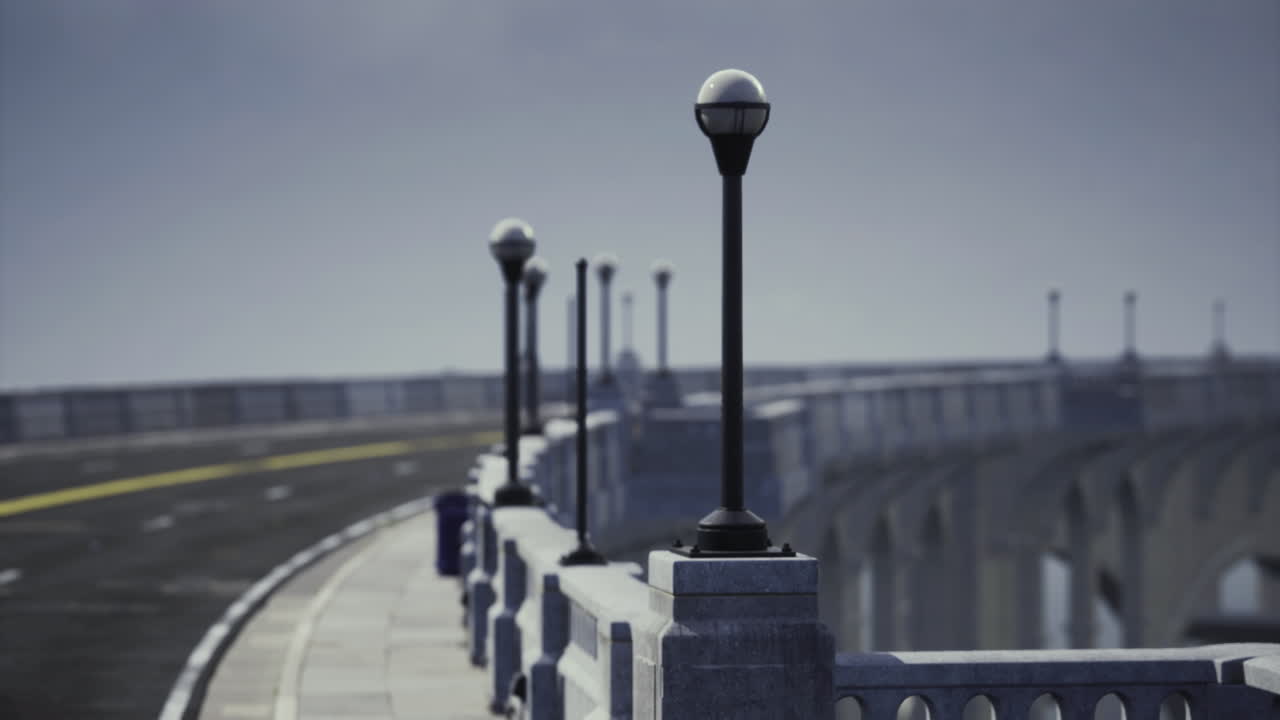 Jembatan berdesain indah dengan tiang lampu di samping jalan berkelok saat fajar