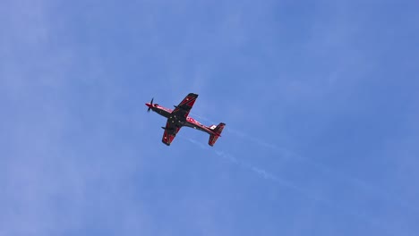 a single aerobatic plane executes impressive maneuvers against a clear blue sky, leaving white smoke trails during the avalon airshow
