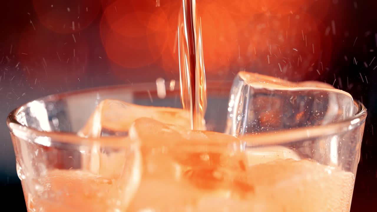 Bicchiere di bibita analcolica. Bibita ghiacciata con bollicine che schizzano al rallentatore su una luce sfocata, sfondo sfocato